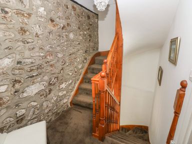 A staircase with wooden banisters and stone wall next to it at The Old Mill in Neyland near Milford Haven