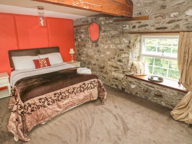 A bedroom with a bed and stone walls and a window at The Old Mill in Neyland near Milford Haven