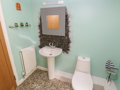 A bathroom with a pedestal sink toilet radiator mirror and small decorative plants at The Old Mill in Neyland near Milford Haven
