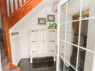 Hallway with a wooden staircase white cabinet on black tiled floor at The Old Mill in Neyland near Milford Haven