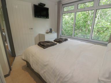 A bedroom with a double bed white bedding towels on bed a chest of drawers and a wall mounted television at The River Lodge in Oban