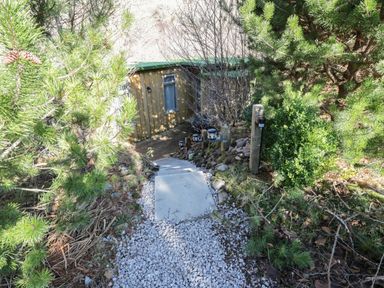 A pathway with stone steps and gravel surrounded by trees leading to a small wooden building at The River Lodge in Oban