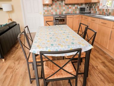 A kitchen and dining area with a table covered with a patterned tablecloth and six chairs at The Shieling in Warkworth