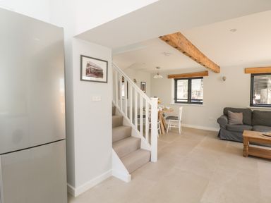 A dining area and living room with a staircase and a refrigerator at Kingfisher 2 The Old Stables in Witney