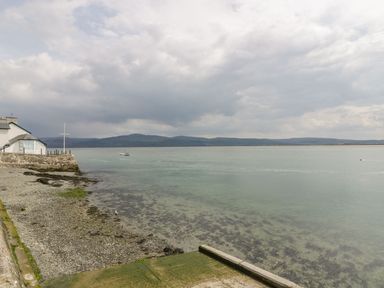 A coastal view with a pebble beach a building and mountains in the distance at The Look Out in Aberdovey