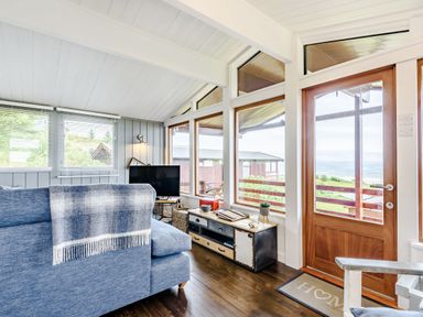 A living room with blue sofa wooden door and large windows showing outside view at The Look Out in Aberdovey