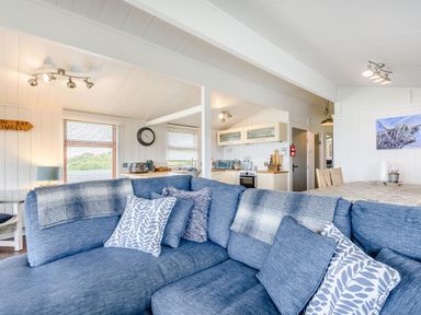 An open plan living room and kitchen with a blue sofa and dining table at The Look Out in Aberdovey