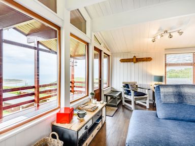 A living room with large windows overlooking a balcony and sea at The Look Out in Aberdovey