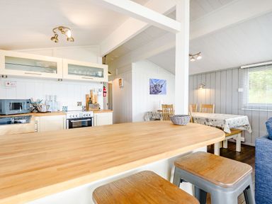 A kitchen with wooden countertops stools a dining area with table and chairs and a window at The Look Out Aberdovey