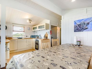 A kitchen and dining area with a table covered with a patterned tablecloth and wooden chairs at The Look Out in Aberdovey