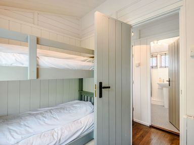 A bedroom with bunk beds and a partially open door leading to a bathroom at The Look Out in Aberdovey