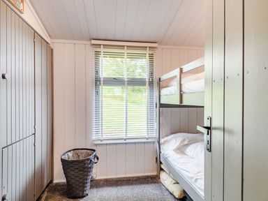 A room with bunk beds a window a laundry basket and a built in wardrobe at The Look Out in Aberdovey