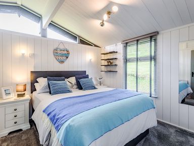 A bedroom with a bed and bedside tables and a window with blinds at The Look Out in Aberdovey