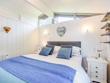 A bedroom with a bed with blue pillows and a blue blanket and white bedside tables at The Look Out in Aberdovey