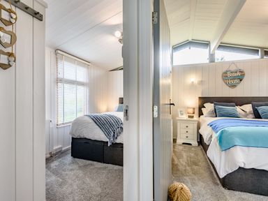 Two bedrooms with beds pillows nightstands and windows at The Look Out in Aberdovey