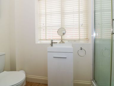 A bathroom with a toilet sink cabinet shower and window blinds at 26 Burtons Mill in Stalham