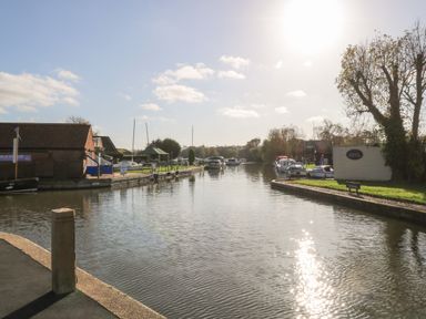 A waterway with boats docked along both sides and buildings nearby at 26 Burtons Mill in Stalham