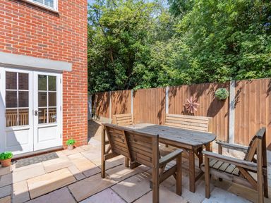 A patio area with wooden outdoor furniture and a wooden fence at 26 Burtons Mill in Stalham