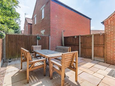 An outdoor patio area with a wooden table and chairs surrounded by wooden fences at 26 Burtons Mill in Stalham