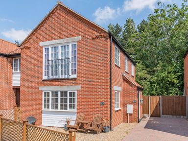 A brick house with white framed windows and wooden chairs outside at 26 Burtons Mill in Stalham