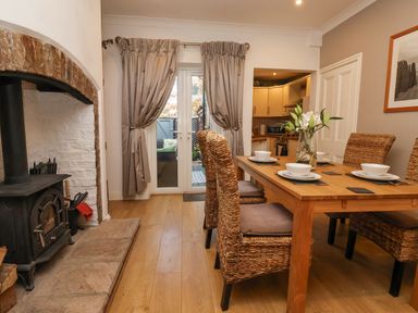 A dining area with wicker chairs around a wooden table and a wood stove next to double glass doors at 202 Salisbury Terrace in York