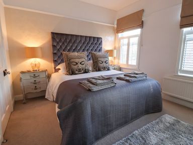 A bedroom with a bed featuring pillows with Buddha faces and bedside tables with lamps at 202 Salisbury Terrace in York