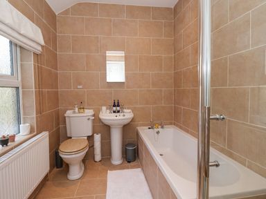 A bathroom with a toilet sink and bathtub with beige tile walls at 202 Salisbury Terrace in York
