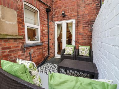 A small outdoor patio with wicker furniture and green cushions at 202 Salisbury Terrace in York