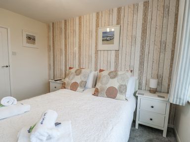 A bedroom with a double bed and nightstands at Daisy Cottage in Benllech