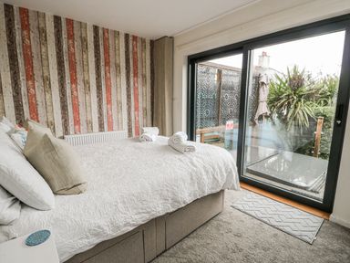 A bedroom with a bed and sliding door leading outside at Daisy Cottage in Benllech