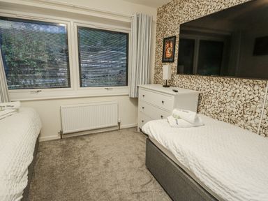 A bedroom with two beds and a dresser at Daisy Cottage Benllech