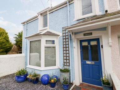 The front entrance of a blue house with a blue door and potted plants at Arwel in Nefyn