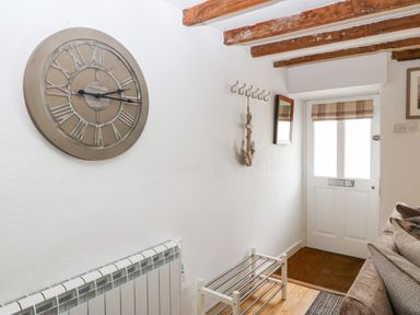 An entryway with a wall clock a coat rack a mirror a door and a shoe rack at Arwel in Nefyn