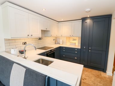 A kitchen with blue and white cabinets a sink and stove at Arwel in Nefyn
