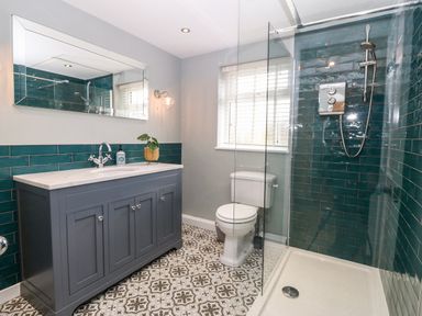A bathroom with a shower area sink vanity toilet and patterned floor at Arwel in Nefyn
