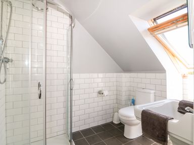 A bathroom with a shower enclosure toilet sink and window at Trevose House in Crantock