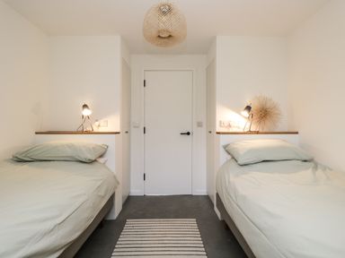 A bedroom with two single beds bedside lamps and a striped rug at High Cogges Farm Holiday Cottages - The Cart Shed in High Cogges near Witney