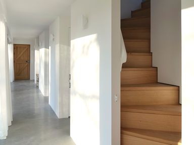 A hallway with wooden stairs and a wooden door at the end at High Cogges Farm Holiday Cottages - The Cart Shed High Cogges near Witney