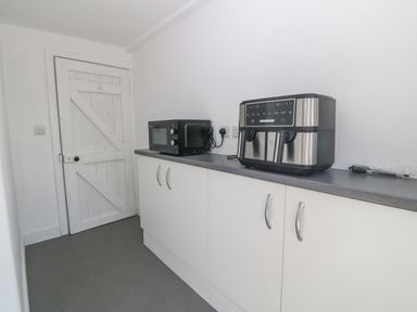 A kitchen counter with a microwave and a coffee machine at Glanffraw Aberffraw Ty Croes