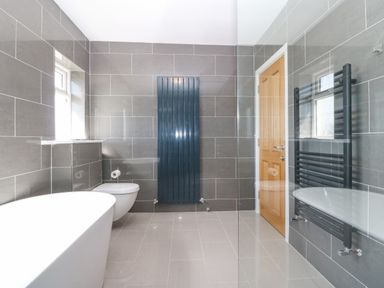 A bathroom with a bathtub toilet and two vertical radiators at Glanffraw in Aberffraw Ty Croes