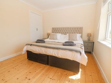 A bedroom with a double bed bedside tables with lamps and a window at Glanffraw in Aberffraw Ty Croes