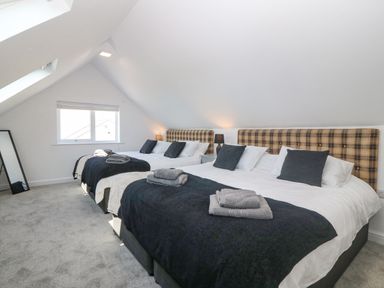 A bedroom with two double beds pillows lamps and a window at Glanffraw Aberffraw Ty Croes