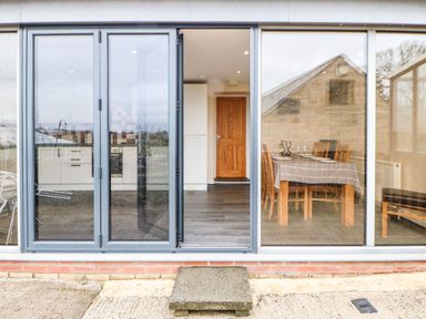A kitchen and dining area visible through glass folding doors at Houghton North Farm Cottage in Heddon-on-the-Wall near Hexham