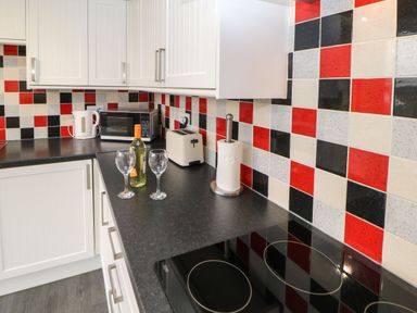 A kitchen with white cabinets a black countertop a microwave kettle toaster paper towel and wine glasses at Houghton North Farm Cottage in Heddon-on-the-Wall near Hexham