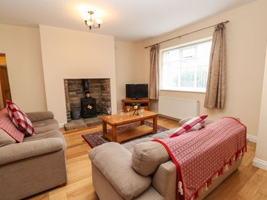 A living room with two sofas and a wooden coffee table in front of a brick fireplace with a wood burning stove at Houghton North Farm Cottage in Heddon-on-the-Wall near Hexham