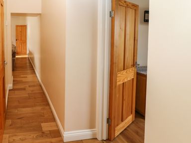 A hallway with wooden floors and doors with one door partially open showing tiled surface at Houghton North Farm Cottage in Heddon-on-the-Wall near Hexham