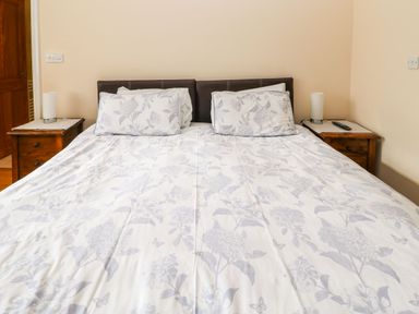 A bed with floral bedding and two pillows between two wooden bedside tables each with a white lamp at Houghton North Farm Cottage in Heddon-on-the-Wall near Hexham