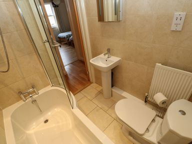 A bathroom with a bathtub shower unit sink toilet and radiator at Houghton North Farm Cottage in Heddon-on-the-Wall near Hexham