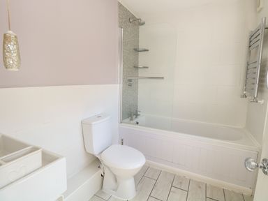 A bathroom with a toilet bathtub shower and sink at Gulls Nest in Pakefield