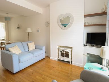A living room with a blue sofa white fireplace and a wall-mounted television at Gulls Nest in Pakefield